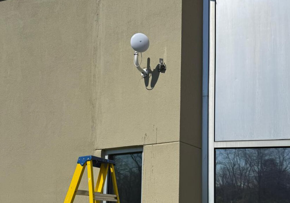 Technician installing network-connected security camera on commercial building