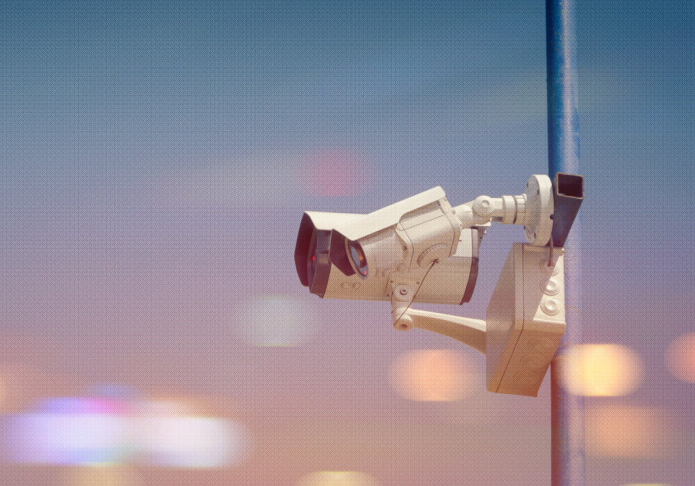 Commercial security camera on pole overlooking city at dusk