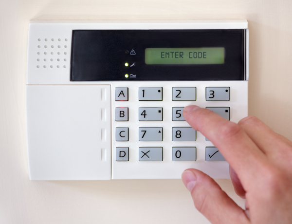 Hand entering code on a commercial alarm system keypad