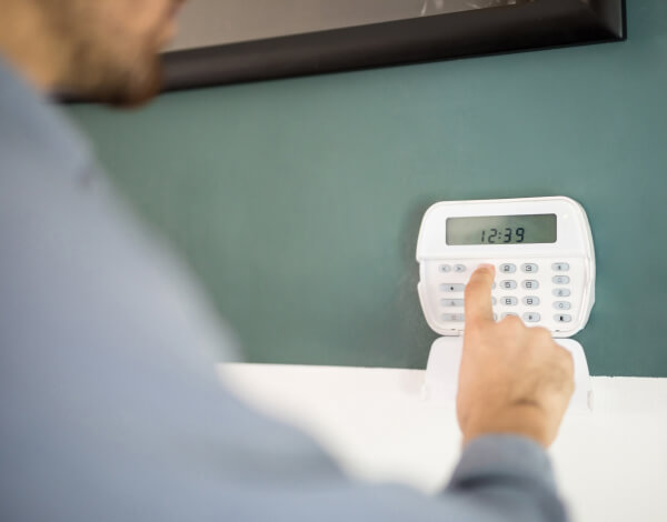 Employee disarming a commercial alarm system at a wall keypad